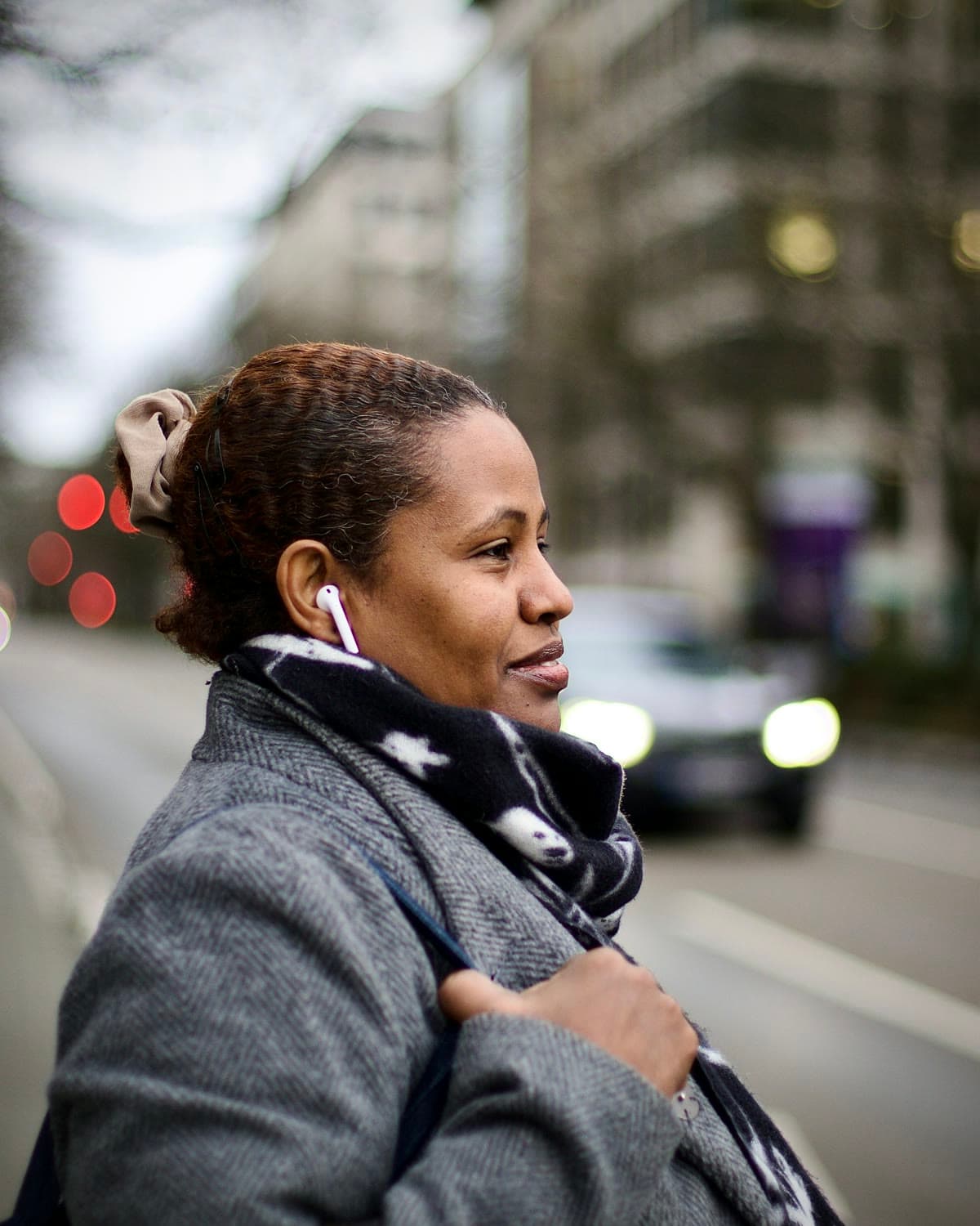 A woman on a city street with a white AirPod in her ear
