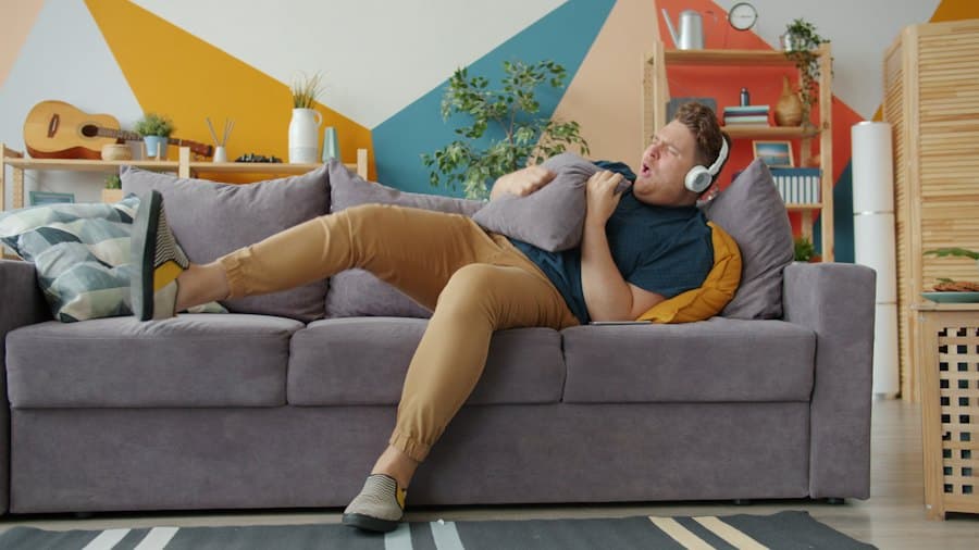 A man stretched out on a sofa, wearing headphones